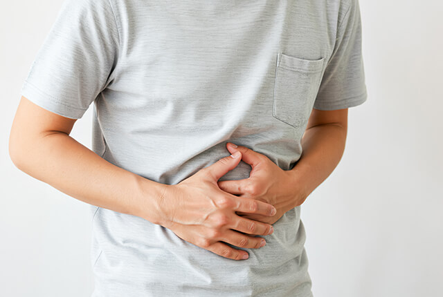 両手でお腹をおさえる男性